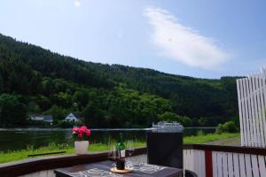 un balcón con una mesa y un barco en el agua en Altes Fährhaus Anno 1 6 3 3 Traumferienwohnung In Exponierter Moselufer Lage, en Traben-Trarbach