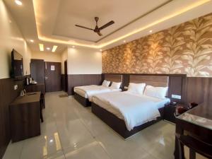 a hotel room with two beds and a ceiling fan at Cottage Club Inn in Almora