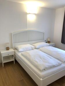 a white bed with white sheets and pillows at Ferienwohnung Design Chalet In Bad Kleinkirchheim in Bad Kleinkirchheim