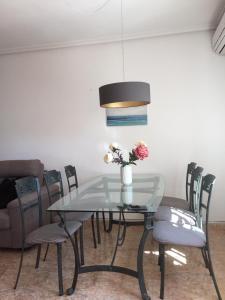 a glass table with chairs and a vase of flowers at Schönes Ferienhaus Mit Pool Und Terrasse in Los Urrutias