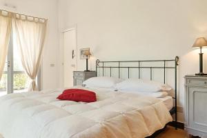 un grande letto bianco con un cuscino rosso di Villa Glicini a Ostra Altre 32 foto