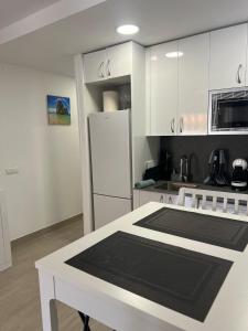 une cuisine avec des armoires blanches et un réfrigérateur blanc dans l'établissement Morning Coffee by the Sea 1 BR Between Capellans and Llevant Beaches, à Salou