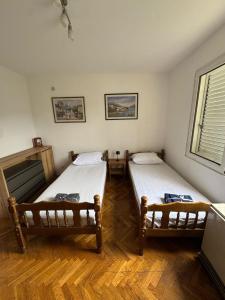 two beds in a room with wooden floors at Adriatic Escape Apartment in Herceg-Novi