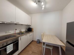 a kitchen with white cabinets and a wooden table at Pension Chen, 2 Doppelzimmer , EBK, separater Balkon in Griesstätt