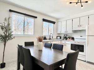a kitchen with a wooden table and chairs and a refrigerator at Le Ranch - with EV Chrger Level 2 in Quebec City
