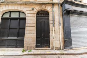 a black door on a building with two windows at Superbe appartement Bordelais plein de charme et lumineux avec terrasse in Bordeaux