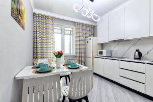 een keuken met witte kasten en een tafel en stoelen bij Комфортные апартаменты в центре города in Astana +15 foto's