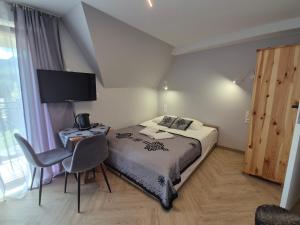 a bedroom with a bed and a desk and a television at Spanie po Zbóju in Kościelisko