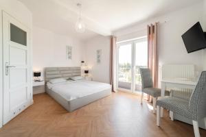 a white bedroom with a bed and a desk and chairs at Pokoje Gościnne Dominika in Jastarnia