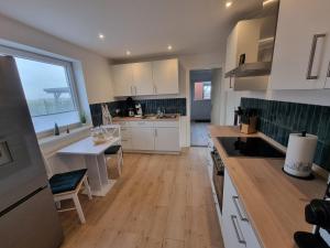 a kitchen with white cabinets and a wooden floor at Ferienhaus AKate - Sauna, Kamin, Garten, 3 Hunde in Kronprinzenkoog