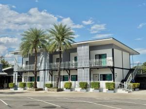 a white building with palm trees in a parking lot at Air Diamond Hotel in Ban Nong Khong