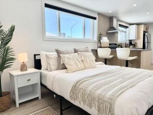 a bedroom with a white bed and a kitchen at Le Tulum - with EV Chrger Level 2 in Quebec City