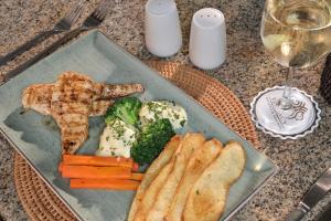 a plate of food with meat and vegetables and a glass of wine at Kwa Maritane Lodge in Ledig