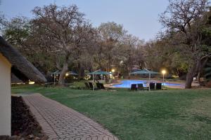 a swimming pool with chairs and umbrellas in a park at Kwa Maritane Lodge in Ledig