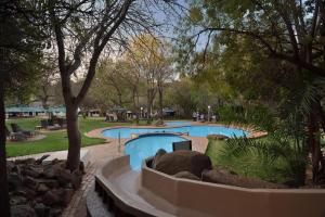 a swimming pool in a park with trees at Kwa Maritane Lodge in Ledig