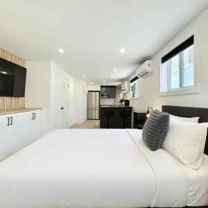 a white bedroom with a large bed and a kitchen at Le Luxueux 2 in Quebec City