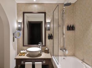a bathroom with a sink and a tub and a mirror at Aldhafra Resort, Vignette Collection by IHG in Madīnat Zāyid +37 photos
