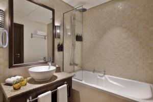 a bathroom with a sink and a bath tub at Aldhafra Resort, Vignette Collection by IHG in Madīnat Zāyid