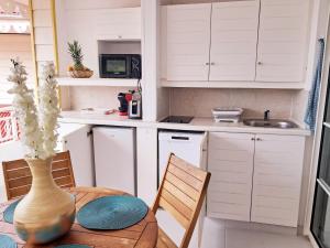 a kitchen with white cabinets and a table with a vase at Appartement Rénové avec accès piscine Superbe VUE MER Village de vacances de Sainte-Anne Guadeloupe OCEAN LILI's EYES in Sainte-Anne