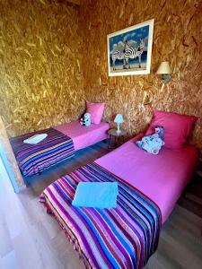 Dos camas en una habitación con sábanas rosas. en Chalet Bois Baobab 5 min à pieds de l'océan, en Montalivet-les-Bains