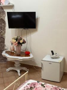 telewizor stojący na stole, na którym leżą kwiaty w obiekcie B&B la reggia w mieście Caserta