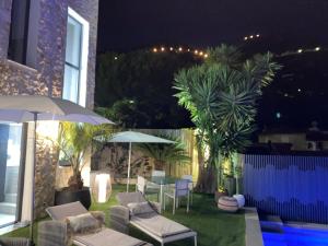 a patio with chairs and umbrellas at night at Luxury villa Panoramic Sea View Near Monaco in Éze