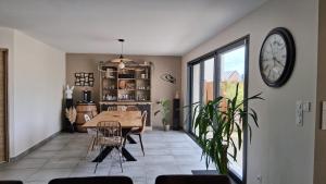 comedor con mesa y reloj en la pared en Maison 170m2 entre ville et campagne, en Changé