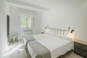 a white bedroom with a large bed and a chair at Mónaco in Valladolid