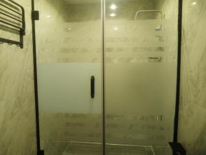 un bagno con box doccia e porta a vetri. di Enchanting Two bedroom Home with Pool a Ikeja
