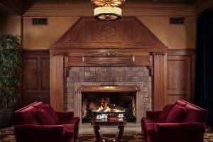a fireplace in a living room with two chairs and a table at Arctic Club Hotel in Seattle