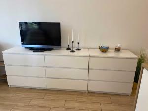 a tv sitting on top of a white dresser at eMeN Apartamenty Jastarnia in Jastarnia +13 photos
