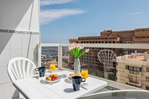 una mesa con un jarrón de flores y fruta en el balcón en Pyr Studio by Alfresco Stays, en Fuengirola