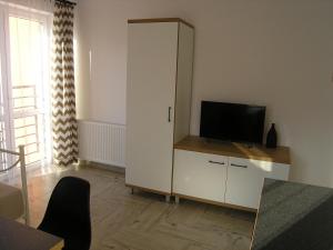 Prima Apartments في كيلسي: غرفة معيشة مع تلفزيون وخزانة بيضاء
