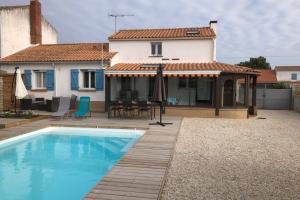 a villa with a swimming pool in front of a house at Maison avec piscine privée chauffée in La Guérinière
