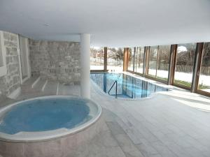 a large swimming pool with a large tub in a building at Luxury Apartment, Panoramic Mountain Views, 5 Star Spa Facilities - 3 Bedroom in Chateau-d'Oex