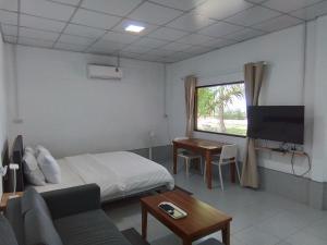 a hotel room with a bed and a tv at The Rock Coco Villa in Ban Laem Pom