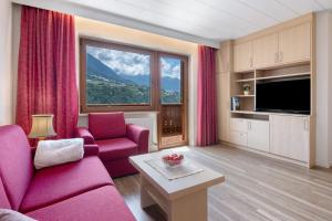 a living room with pink furniture and a large window at Haus Christine in Rifiano