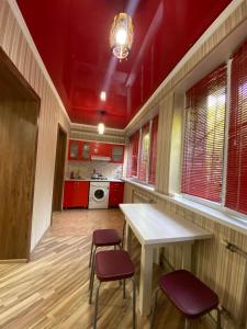 a kitchen with red cabinets and a white table and chairs at Apartment plaza in Shymkent +5 photos
