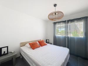 a bedroom with a bed with white sheets and orange pillows at Appartement dans résidence avec piscine in Calvi