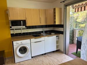 a kitchen with a washing machine and a microwave at Studio piscine parking Cannes in Cannes +5 photos