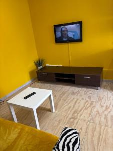a living room with a tv on a yellow wall at Studio piscine parking Cannes in Cannes
