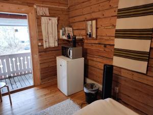 a room with a refrigerator with a microwave on top of it at Maatilamatkailu Jänisvaara aittahuoneet in Kolinkylä