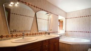 a bathroom with two sinks and a tub and two mirrors at Molí d'en Tarrés in Santa Cristina d'Aro +22 photos