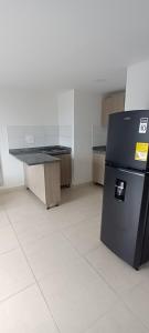 a kitchen with a black refrigerator in a room at Central cerca universidad Autónoma y centros comerciales 2 habitaciones 2 baños parqueadero Privado in Manizales