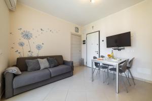 una sala de estar con un sofá y una mesa en Sirio - bilocale comodo a 200 m dal mare e con piscina sul tetto, en Borghetto Santo Spirito
