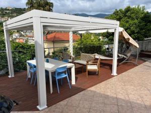 a white pergola on a deck with a table and chairs at Villetta Fioregreco - free parking - Large outdoor space in Sanremo