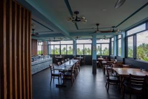 a dining room with tables and chairs and windows at Maa Thundi in Fuvahmulah