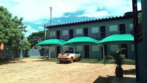 ein vor einem Gebäude mit grünen Regenschirmen geparktes Auto in der Unterkunft Hotel Comodoro in Comodoro