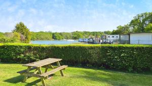 Thistle Cottage في Wootton Bridge: طاولة نزهة خشبية موضوعة على العشب بجوار سياج