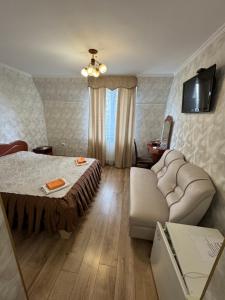 a bedroom with a bed and a couch and a television at Ідилія in Zhensna Polʼska